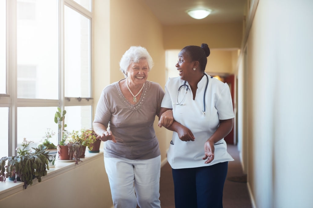 Portrait of happy healthcare worker and senior woman walking together. Senior patient having fun with her home caregiver.